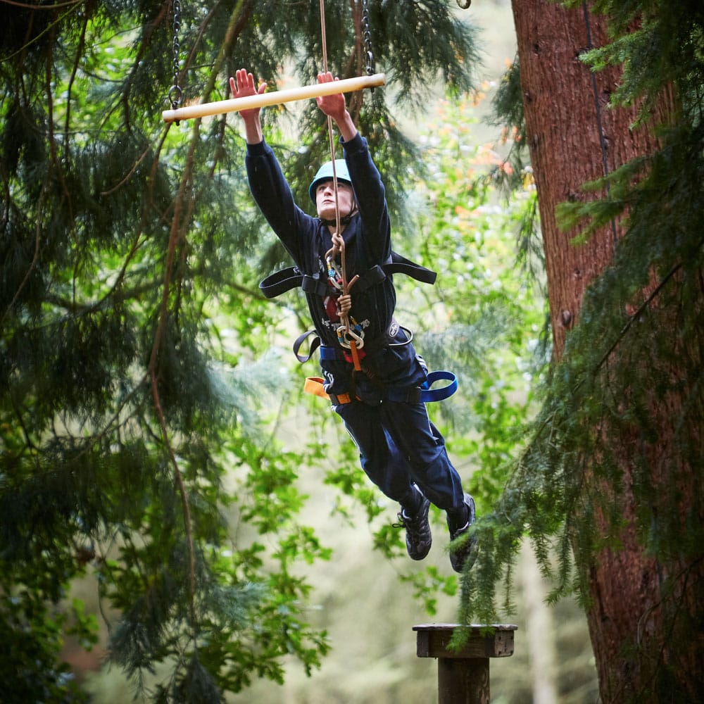 A student leaping from a pillar to reach out for a beam on a trapeze