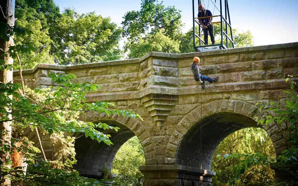 Students abseiling down from a stone bridge at Ford Castle