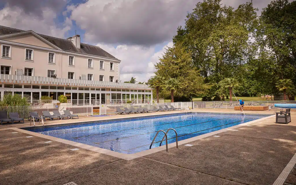 Swimming pool at PGLs Chateau De Grande Romaine with a cleaner on hand cleaning the pool and making it fresh for guests