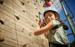 Child navigating the climbing wall at a PGL centre.