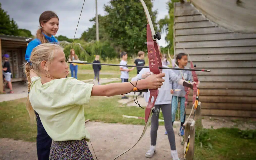 PGL instructor teaching a group of children archery