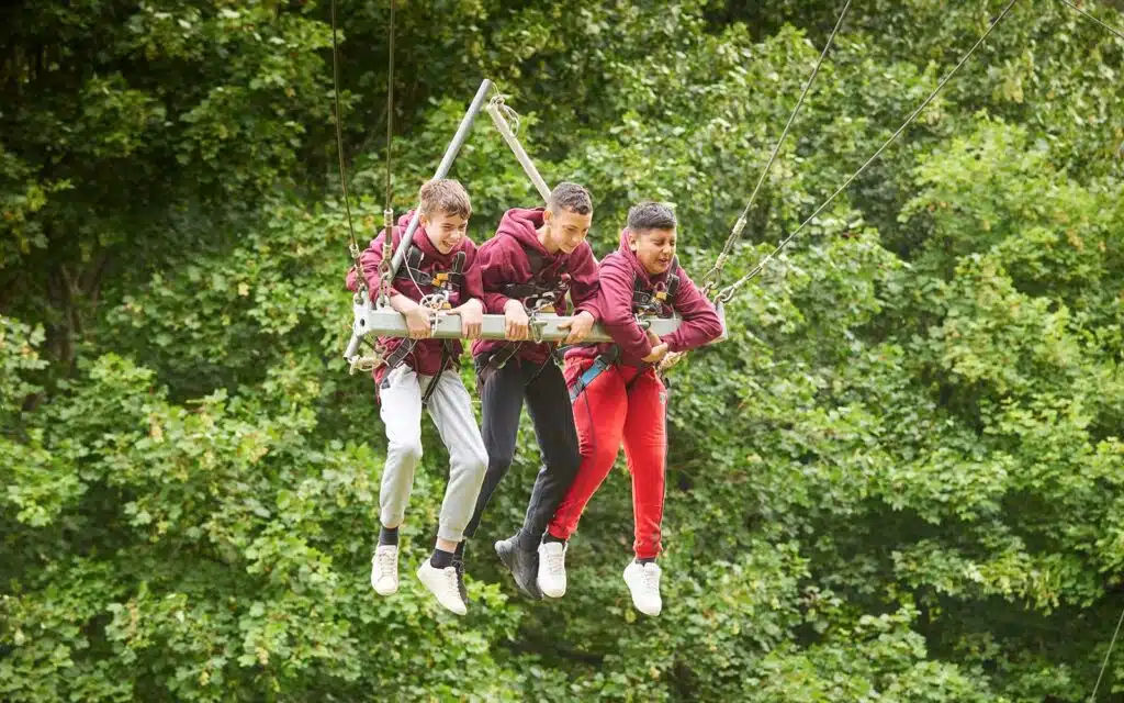 Children on a giant swing clipped in with safety equipment