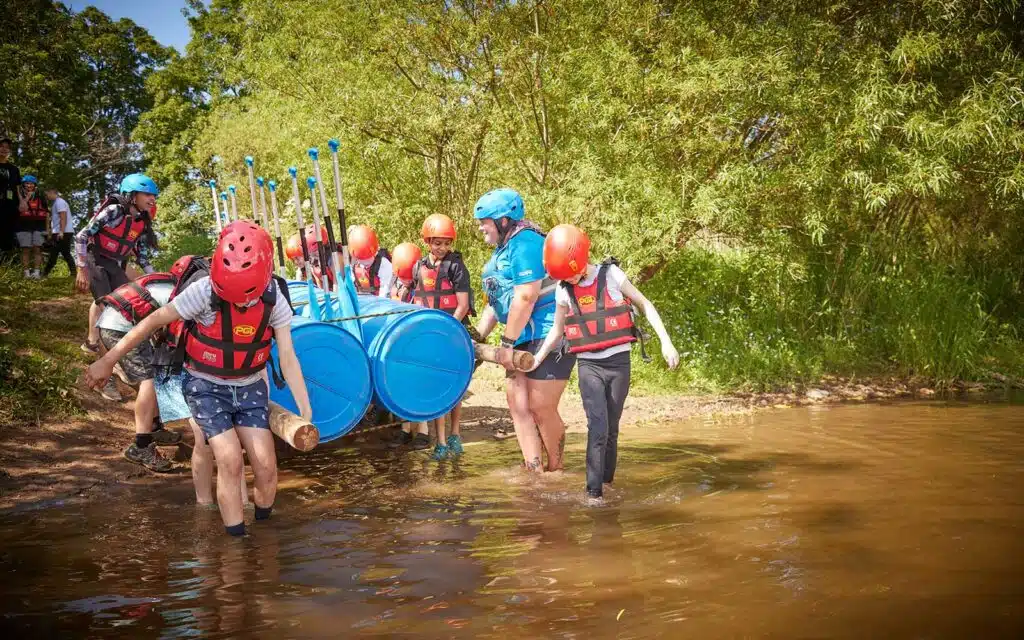 Scouts and a PGL instructor bringing their home built raft into the water