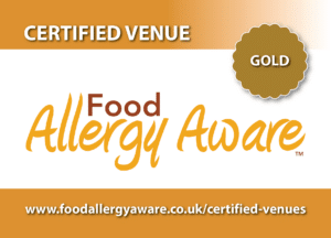 A gold-certified Food Allergy Aware venue sign with website link and the text “CERTIFIED VENUE” and “GOLD” on a gradient background.