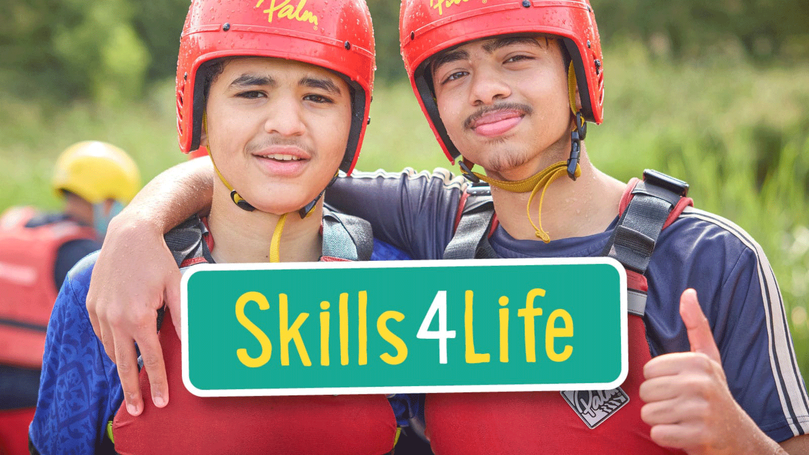 Two teenagers in red helmets and life vests pose together outdoors, smiling with arms round each other. The text “Skills4Life” is overlaid on the image.